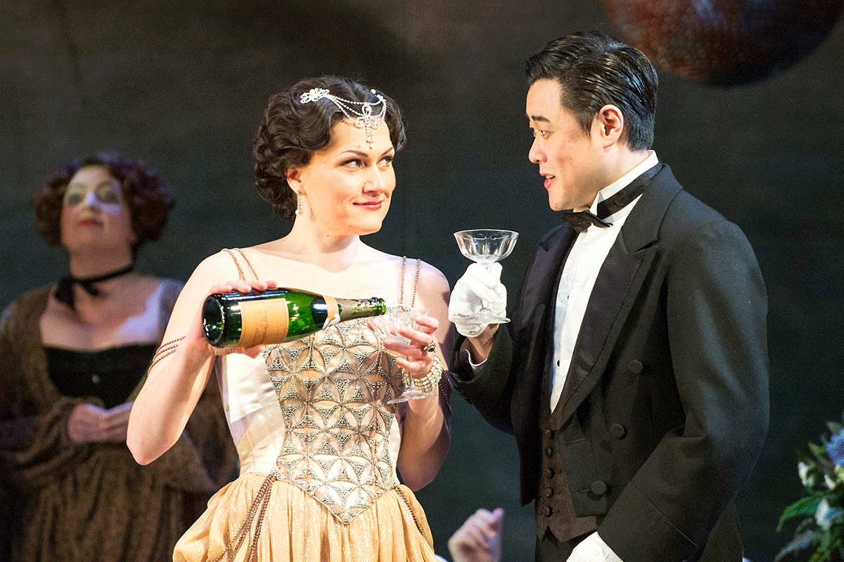 Man and woman in glamorous 1920's clothing toast with glasses of champagne