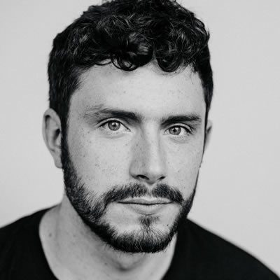 A man with short curly hair and a beard.
