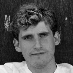 A man wearing a white shirt with tousled hair.