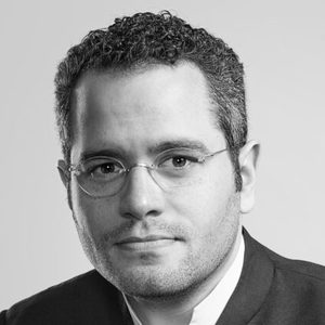 A man with short curly hair and glasses.