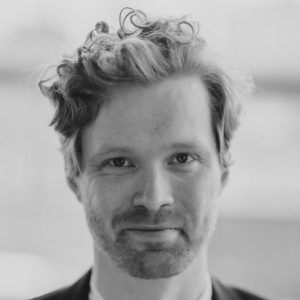 A man with curly ginger hair and a beard.