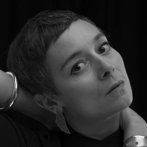 A woman with short dark hair wearing bracelets.