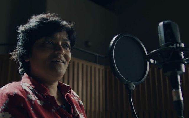 A woman with a red top in front of a microphone.