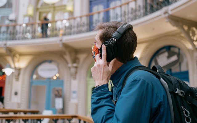 A man stands in Leeds Corn Exchange wearing headphones.