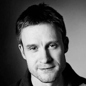 A man with short hair and stubble.
