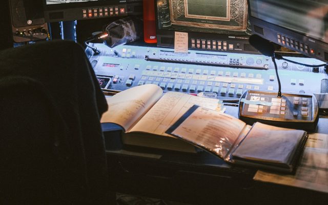 A mixing desk with three screens in front of it.