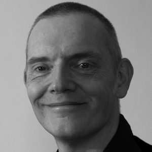A man with cropped hair wearing a black shirt.
