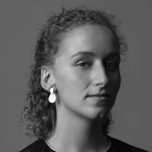 A woman with curly hair wearing earrings.