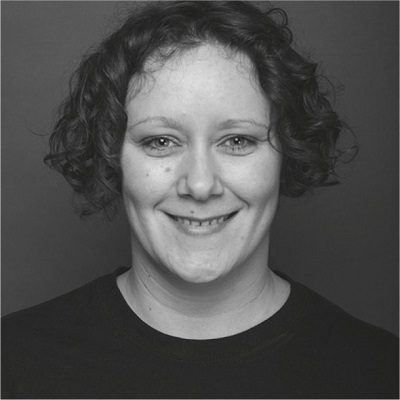 Black and white head shot of a smiling woman with curly hair
