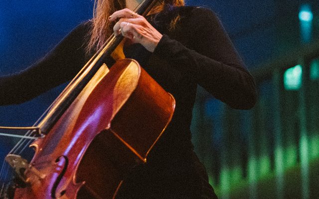 A woman in a black top plays the cello.