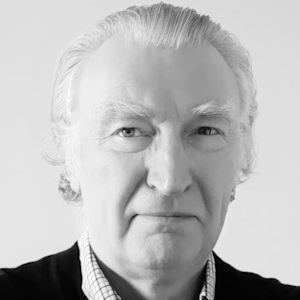 A man with grey hair wearing a shirt and blazer.