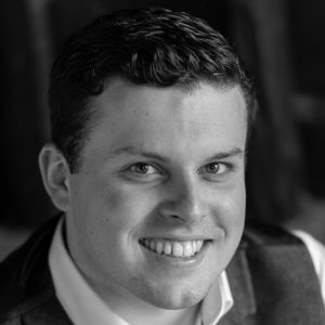 A man wearing a waistcoat and smiling.