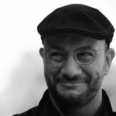A man wearing round glasses and a flat cap.