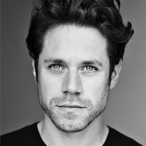 A man with dark hair and stubble.