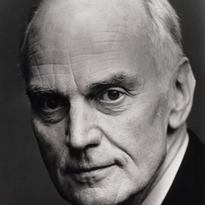A man with short white hair wearing a shirt and jacket.