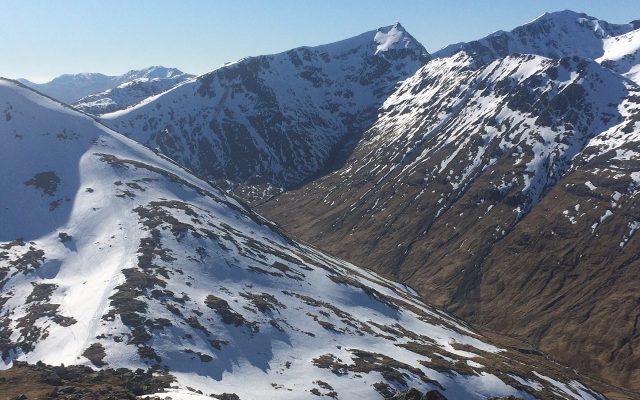A range of snow-capped mountain peaks under a blue sky