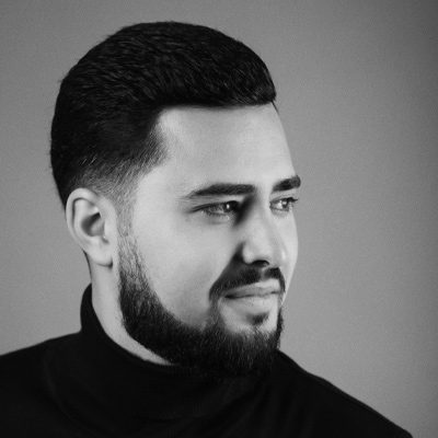 An image of a man wearing a dark polo-neck top with a beard