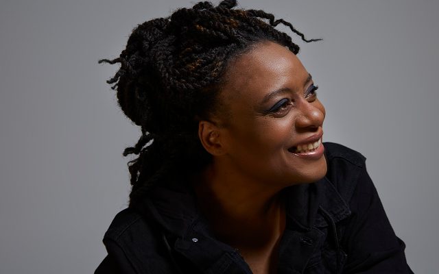 A woman with braided hair smiles in half-profile