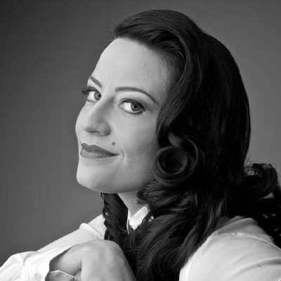 A woman with long dark hair in a white shirt.