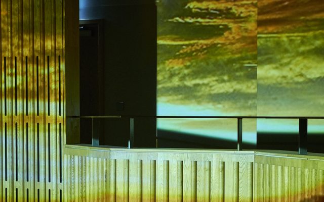 The wood panel walls of the Howard Assembly Room with clouds projected on them.