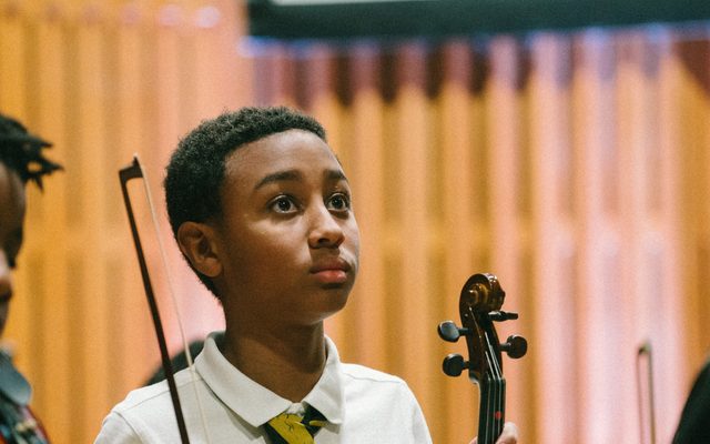 Three children holding violins.