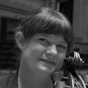 Jessica Burroughs 300 x 300 A woman smiling with the top of a cello beside her face.