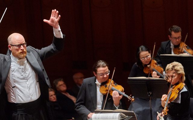 Conductor Ben Palmer performs at a concert in front of a full orchestra