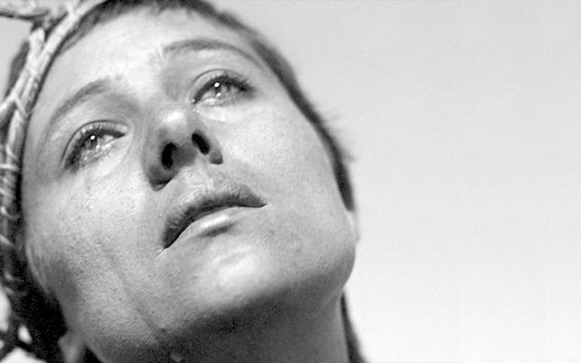 A woman wearing a wooden crown in tears.