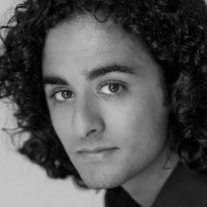 A man with dark curly hair wearing a black shirt.