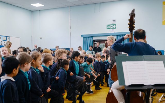 Primary schoolchildren listening to an orchestra in their school hall