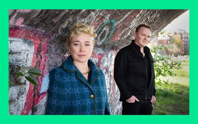 A man and woman standing under a bridge with graffiti