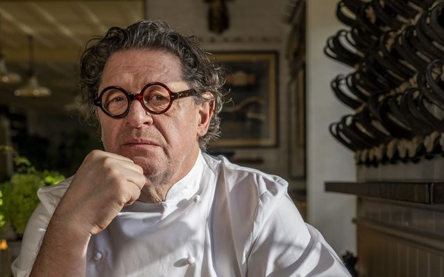 A man with round glasses wearing a chef's smock.