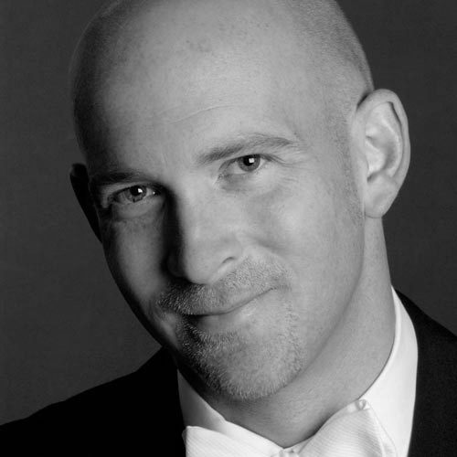 michaelenglandsq A bald man wearing a suit jacket and shirt with white bow tie.