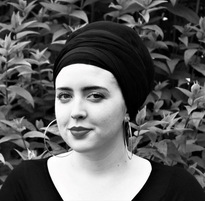 Jaz Manville A young woman wearing large hoop earrings and a headwrap.