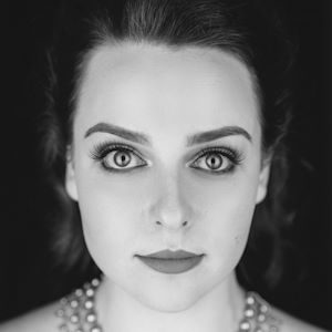 A woman with dark hair wearing a pearl necklace.