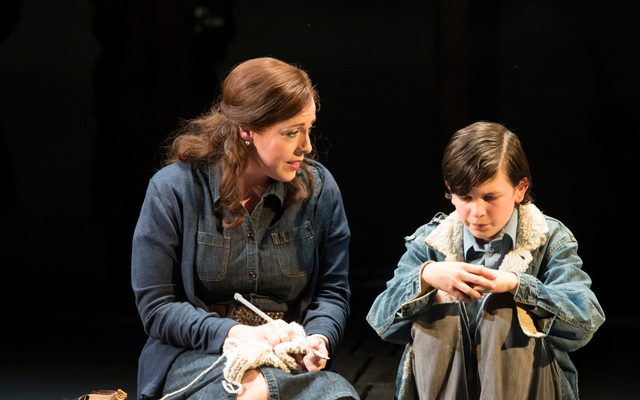 A woman sits besides a young boy, who looks unhappy.