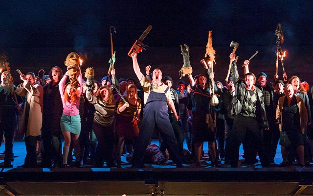 An angry mob holding weapons and lit torches