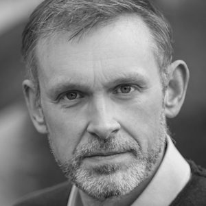 A man wearing a suit with short hair and a short beard.