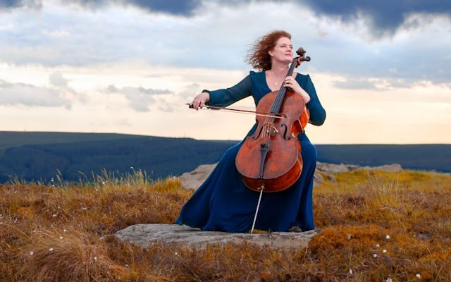 A woman playing cello in the moors.