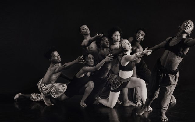 A group of dancers all reaching towards the right.