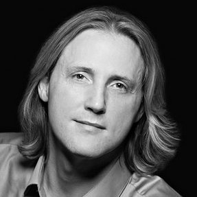 A man with long hair wearing a shirt.