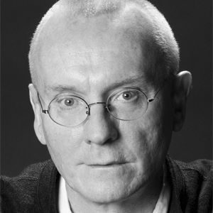 A bald man with round glasses.