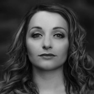 A woman with should length curled hair.