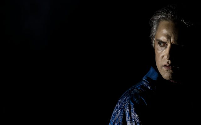 A portrait of a man in a blue shirt. He is half in shadow.