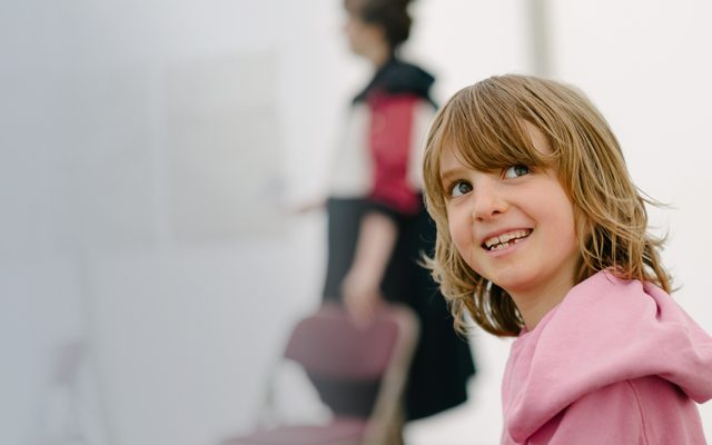 Young boy with longish hair looks back smiling at the camera