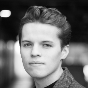 A man with short hair wearing a blazer.