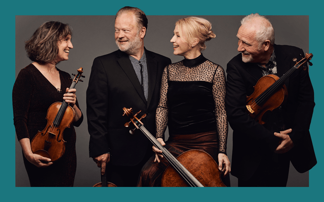 Two men and two women all dressed in black smile whilst clutching classical instruments