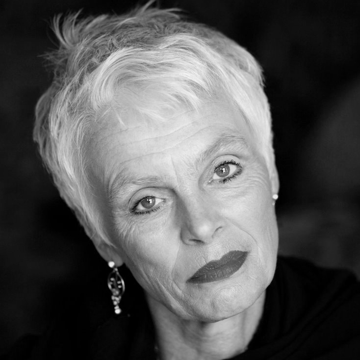 Fiona-Kimm A woman with short white hair wearing large earrings.