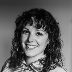 Hannah-Sibai1 A woman smiling into the camera. She has dark curly hair.
