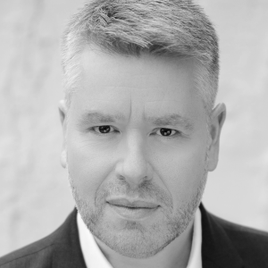 A man with short grey hair wearing a shirt and jacket.